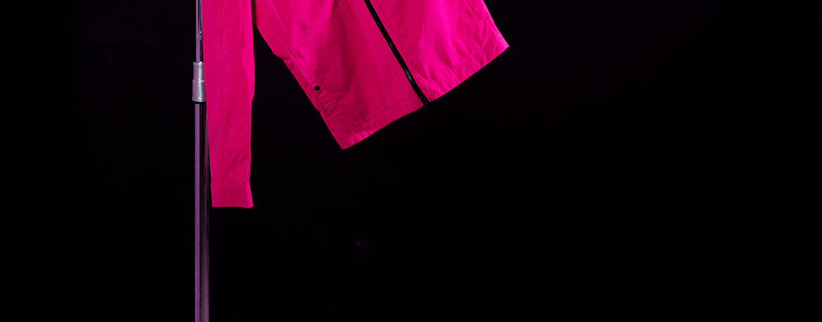 A still life of a FLANNELS X C.P. Company exclusive pink overshirt with the C.P. Company lens on the sleeve