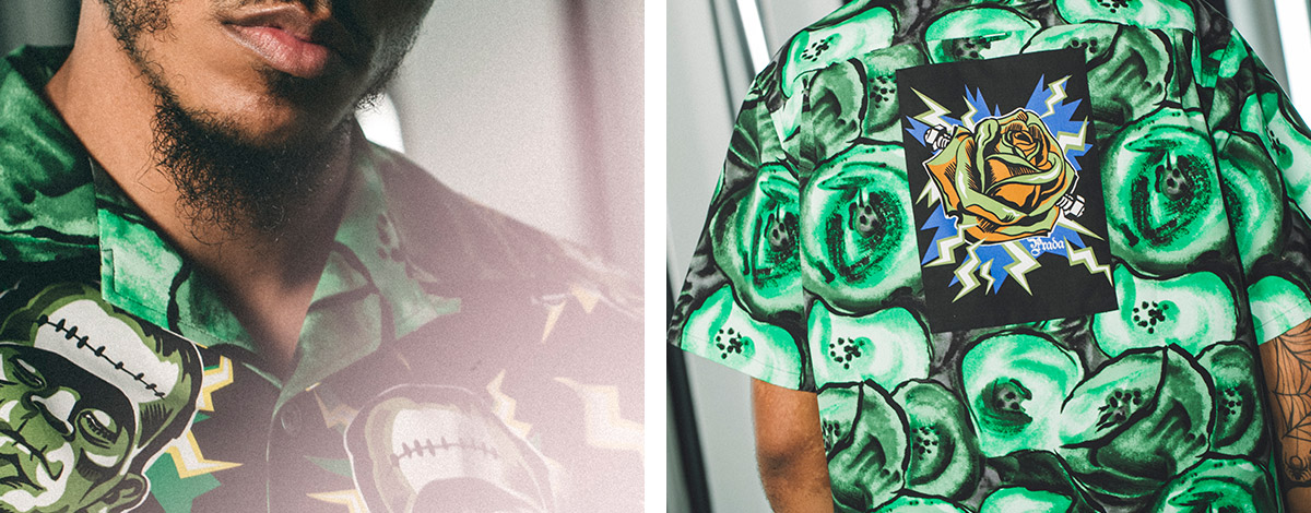 A close-up of rapper AJ Tracey's face wearing an all-over green moster-print Prada short-sleeved shirt