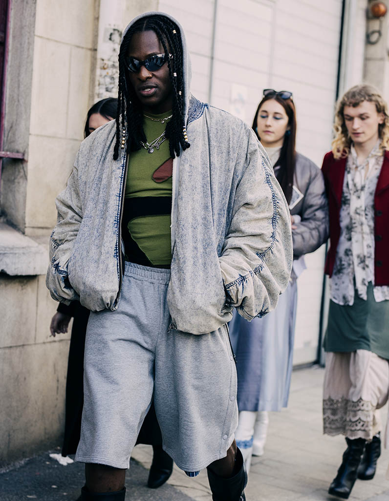 Street style image of a man wearing grey shorts and a denim jacket