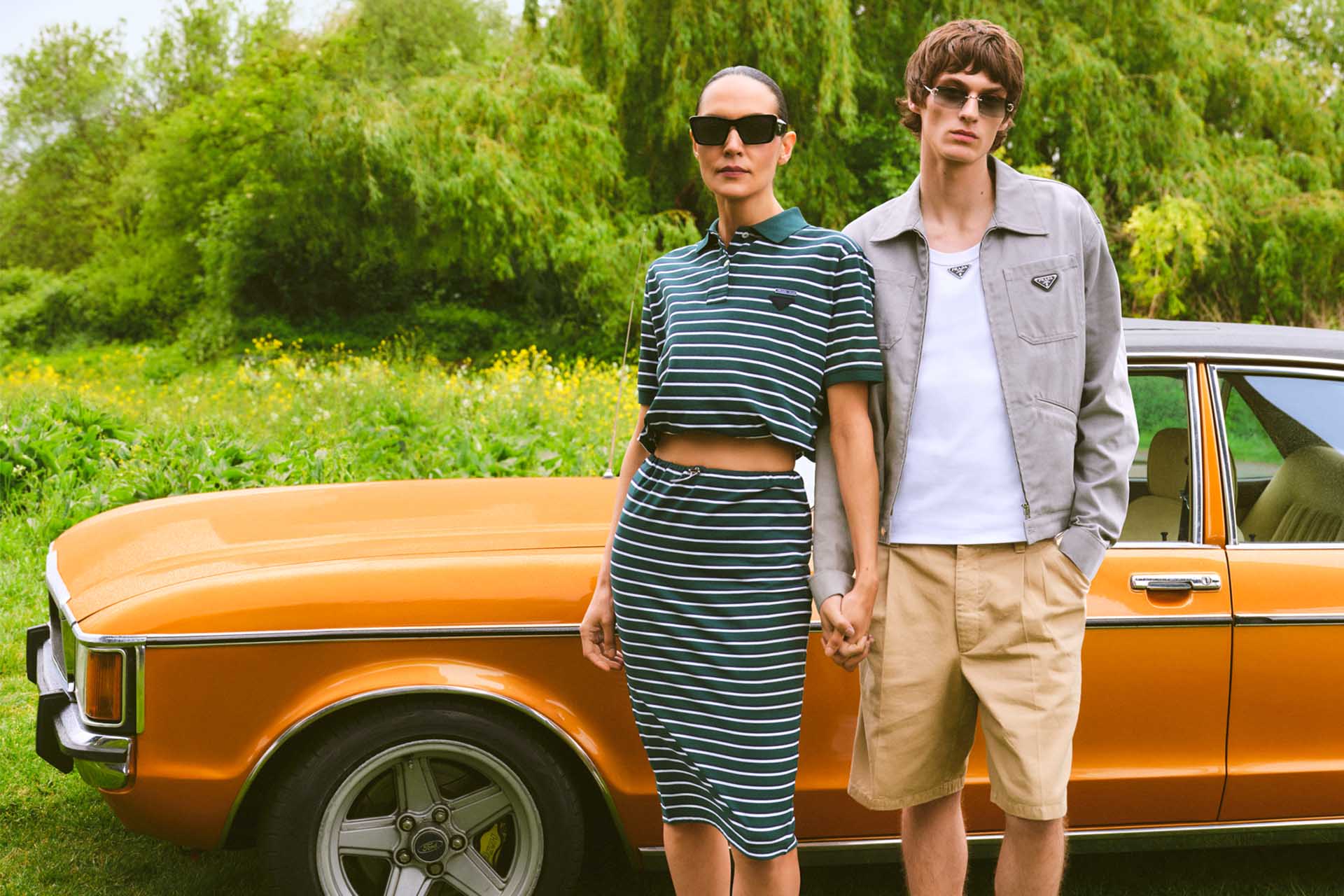 one female model and one male model sat on  a metal bench