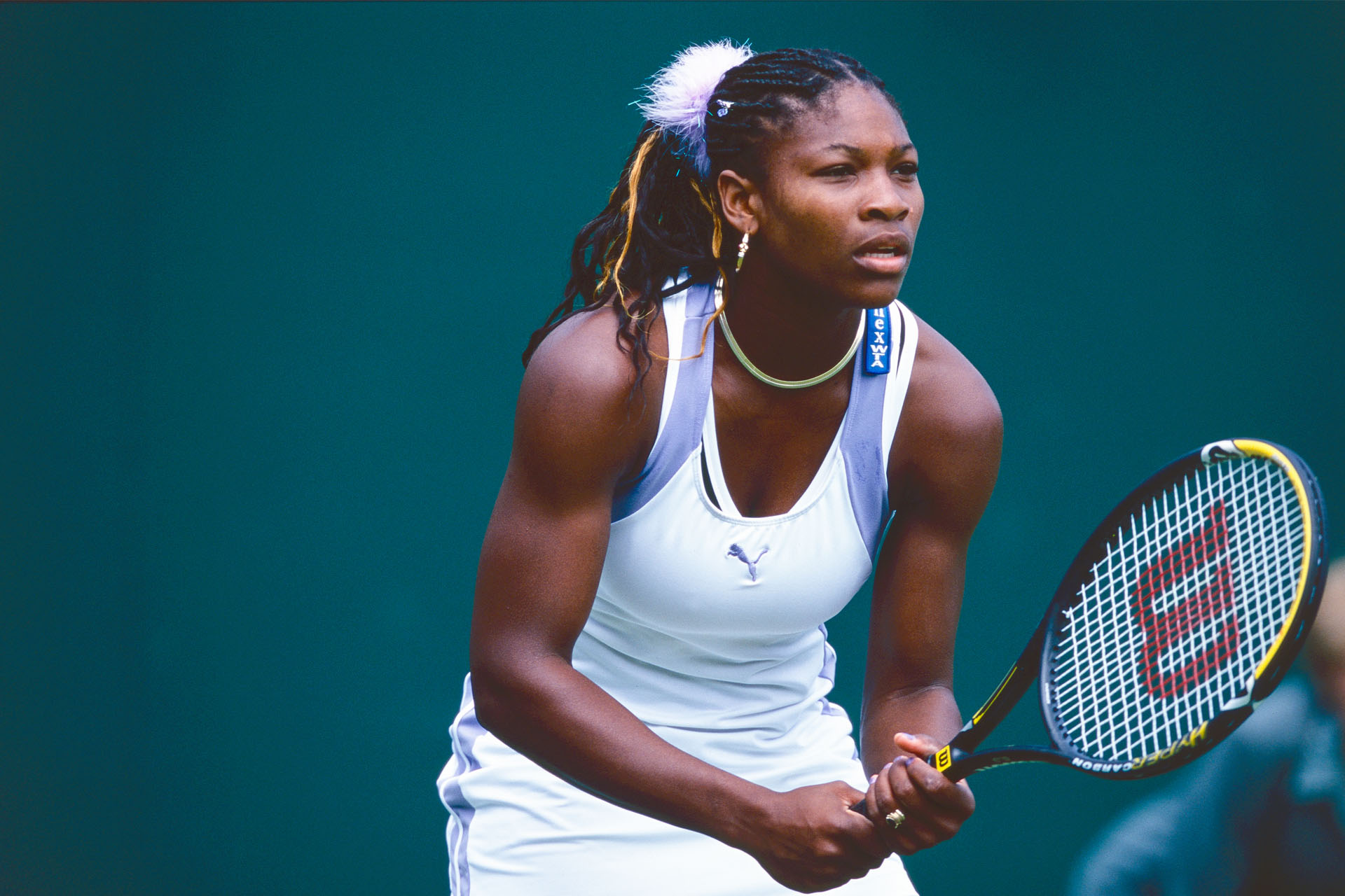 Serena Williams playing tennis in Puma tennis whites, holding racket 
