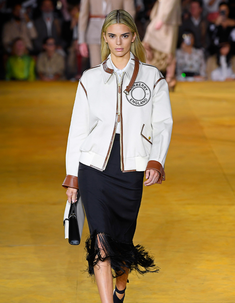 Kendall Jenner in black skirt, Burberry logo jacket and clutch