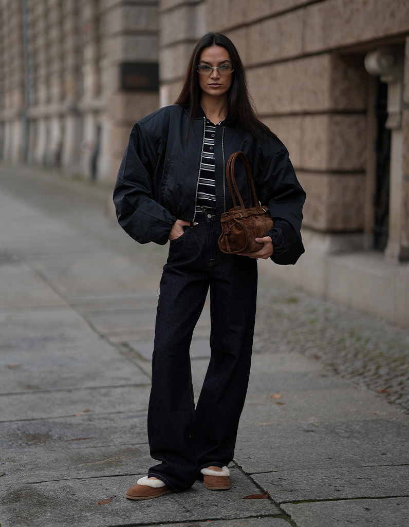 women in jeans, bomber jacket and striped polo