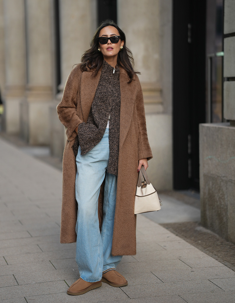 women in denim jeans, wool long coat and brown knit top.