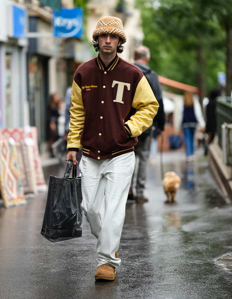 man in bucket hat, white trousers and Letterman jacket 